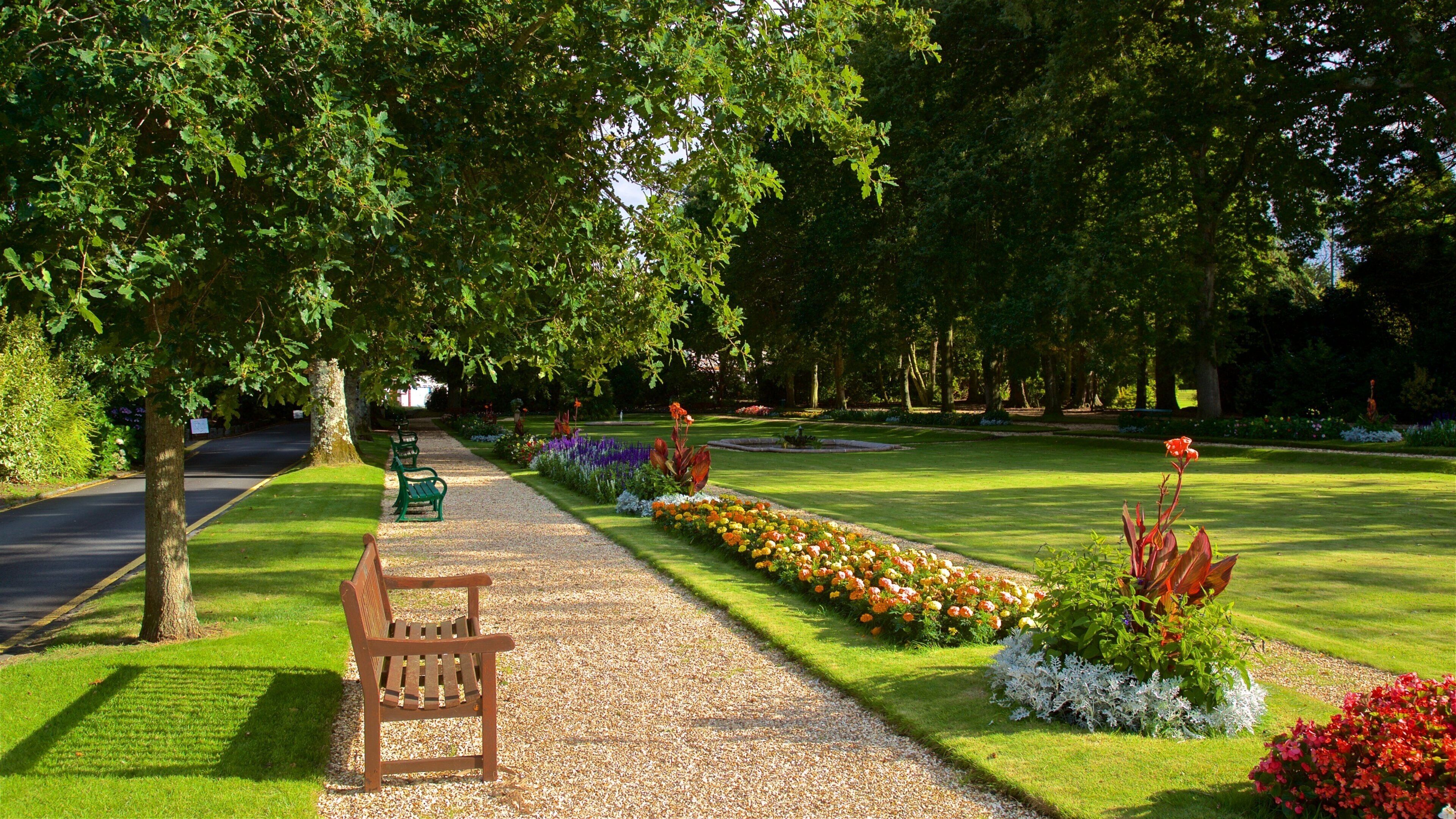 A park with a gravel path, benches, and flower beds.