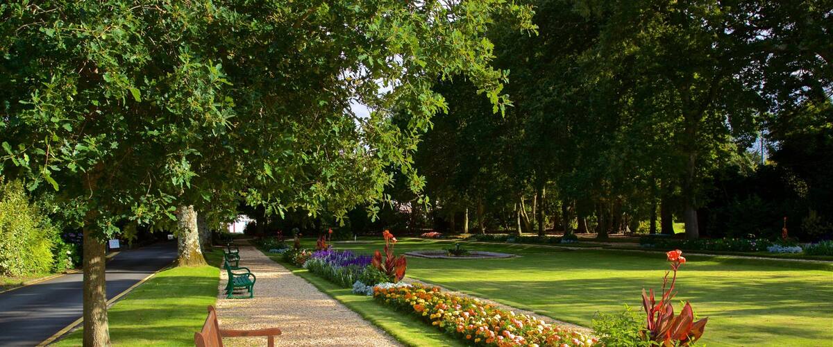 A park with a gravel path, benches, and flower beds.