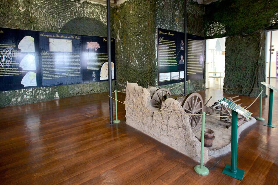 Una exposició històrica amb panells de fusta i una maqueta d'una fortificació amb canons.