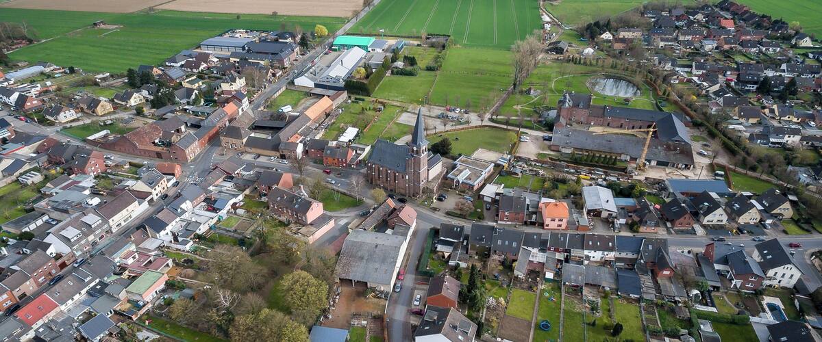 An aerial view of a small town with a mix of residential and commercial buildings, surrounded by green fields and open land.