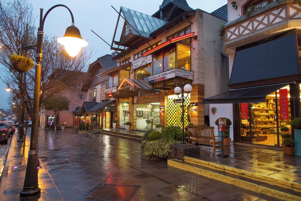 A wet street with shops and a bell-shaped street lamp.