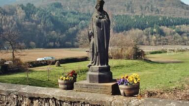 A statue of a person in a field with mountains in the background.