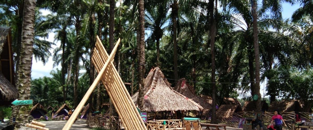 A rustic village with bamboo structures, thatched-roof huts, and palm trees.