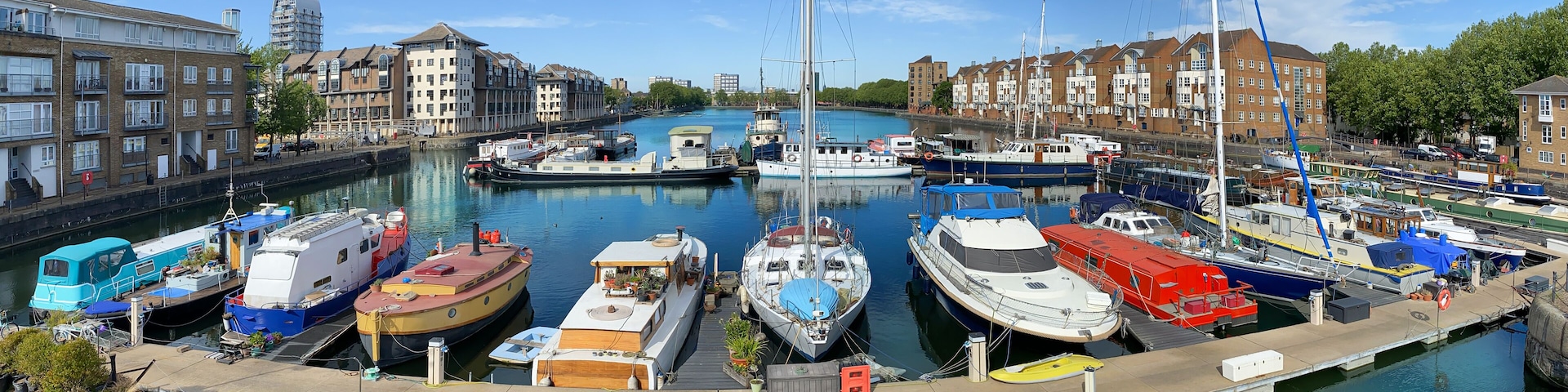 Panorama of Dockland Heritage in a sunny day with traditional boats and sailboats on the coast of Thames river in London