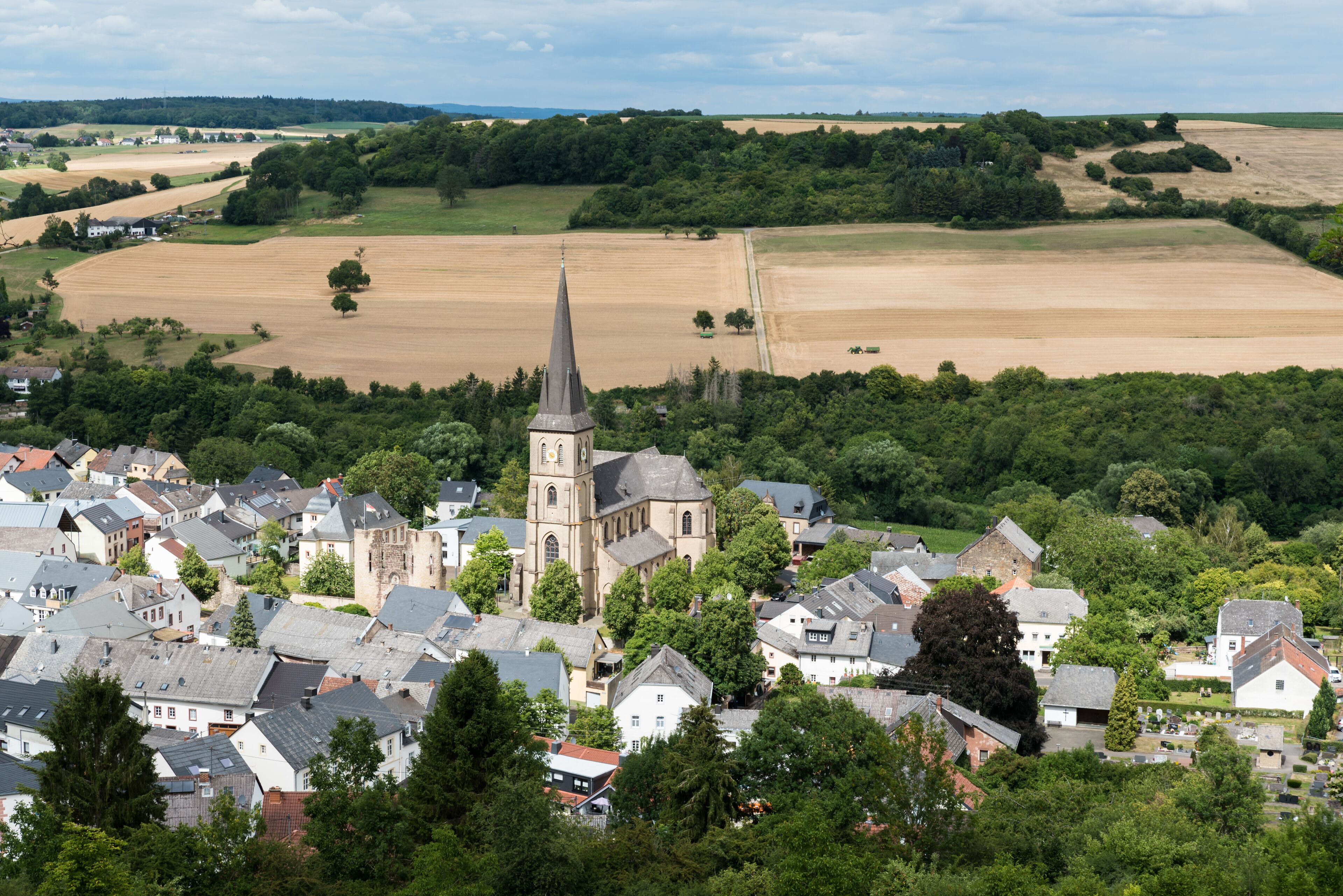 A town with a prominent church, surrounded by fields and greenery.