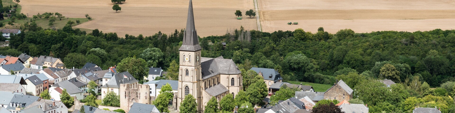 A town with a prominent church, surrounded by fields and greenery.
