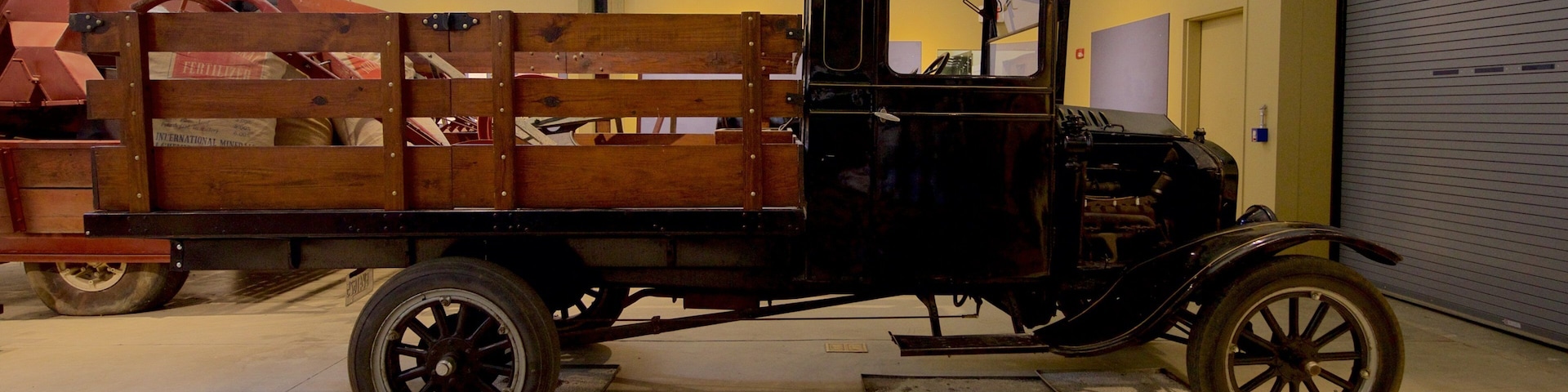 A vintage truck with a wooden bed in a museum.