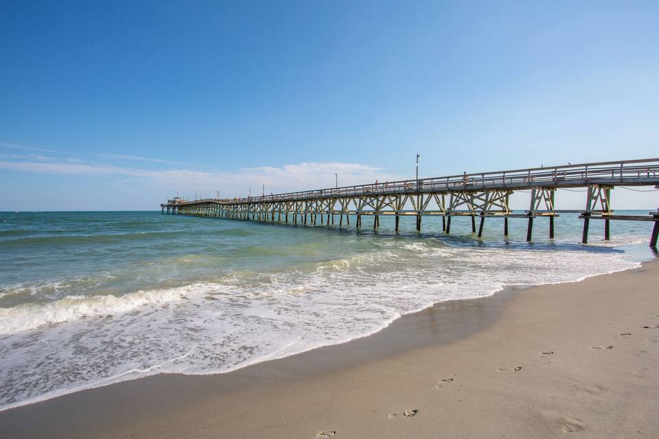A pier extending into the ocean with clear skies and calm waters.