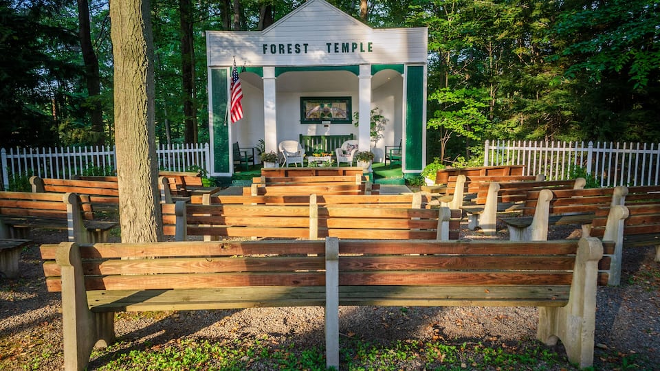 A gazebo labeled "Forest Temple" surrounded by wooden benches and a white picket fence.