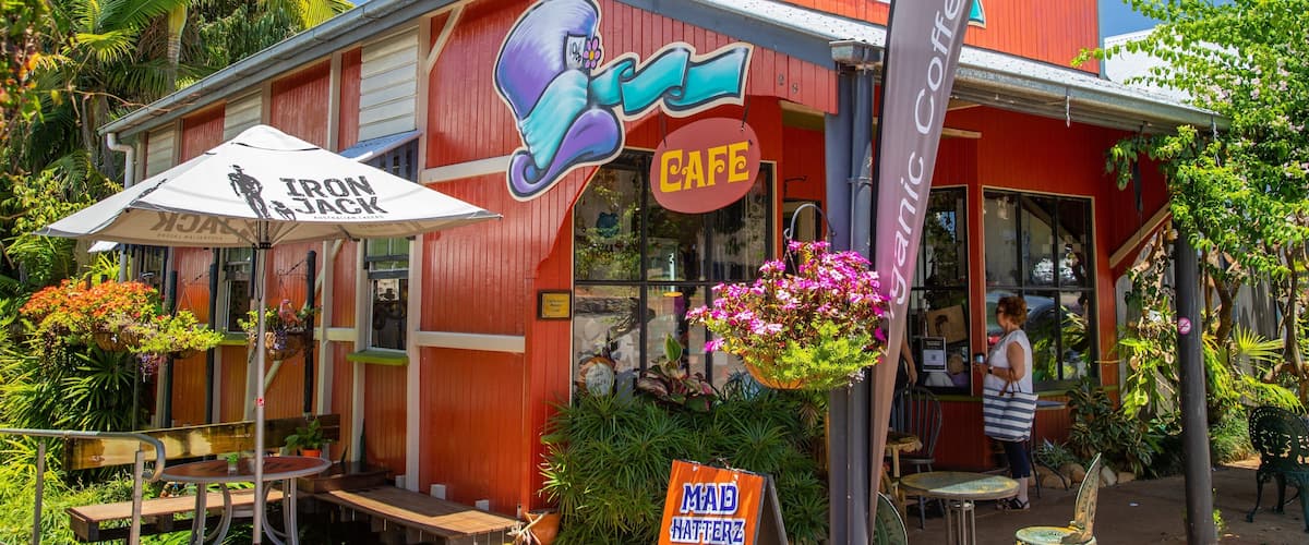 A red building with a cafe sign, outdoor seating, and a 'Mad Hatters Cafe' sign.