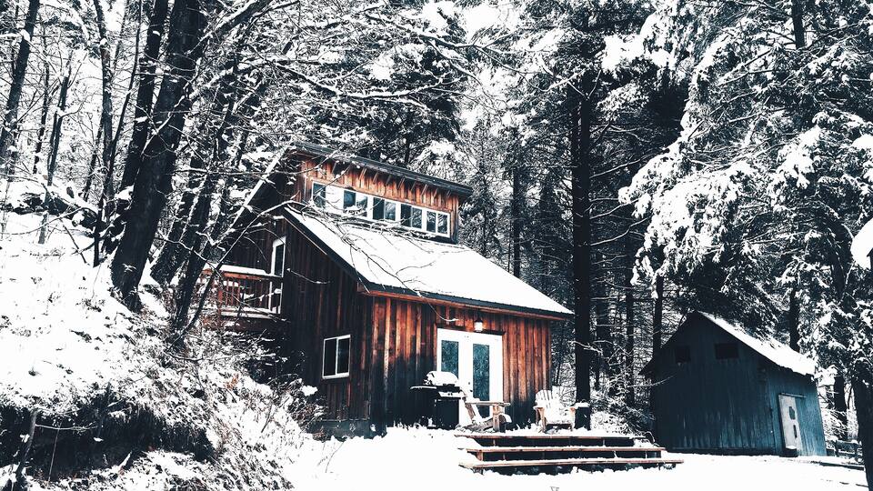A wooden cabin surrounded by snow-covered trees.