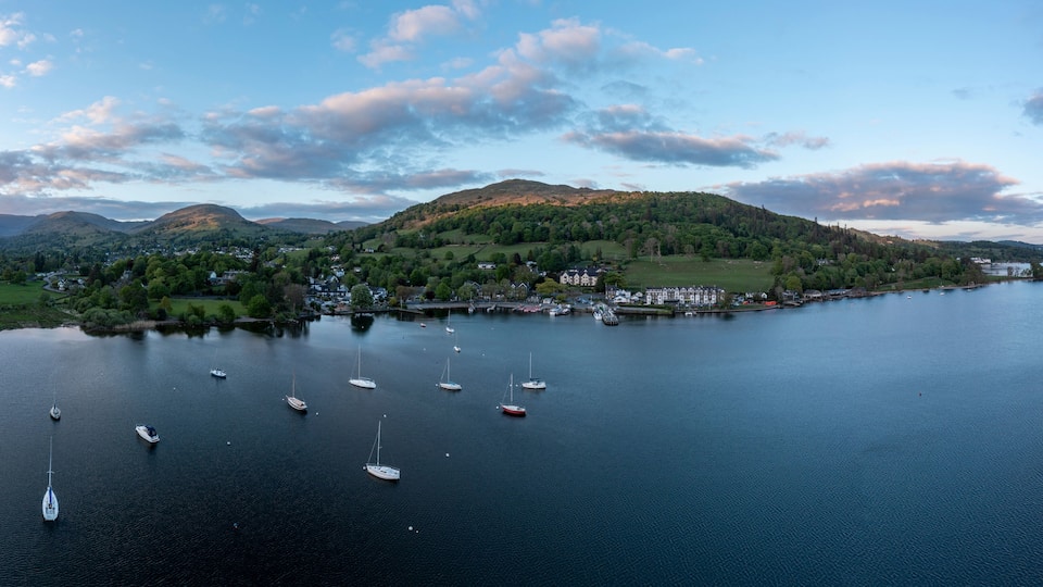 A lake with sailboats, surrounded by hills and a small town.