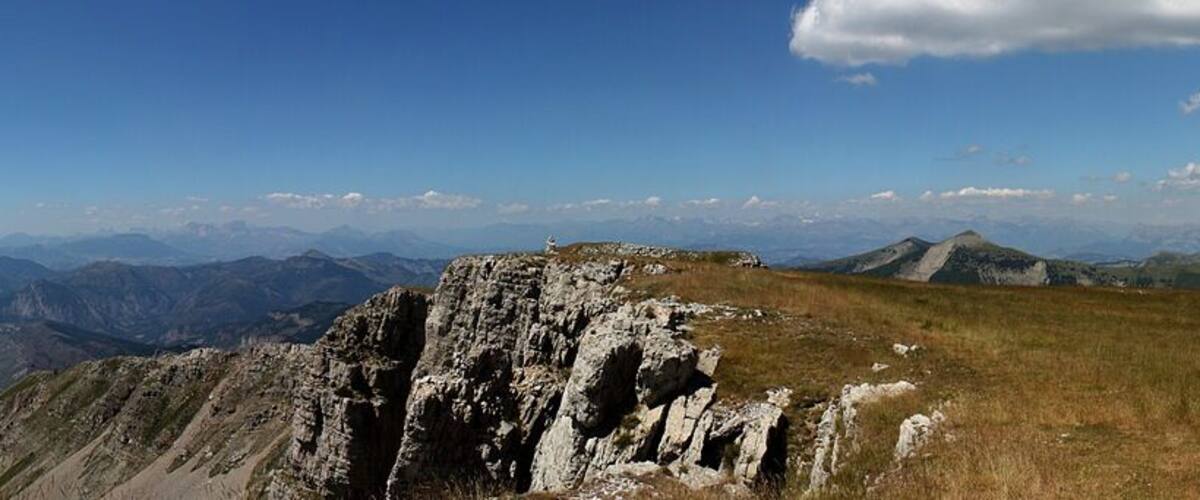 A panoramic view of a mountain range with clear skies and distant peaks.