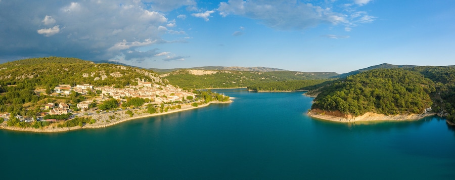 Une ville côtière bordée d’un lac, entourée de collines et de montagnes.