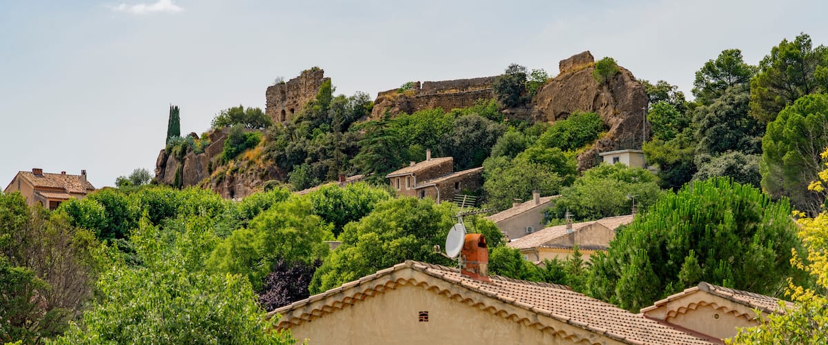 A hillside with a castle ruin, lush greenery, and traditional houses.