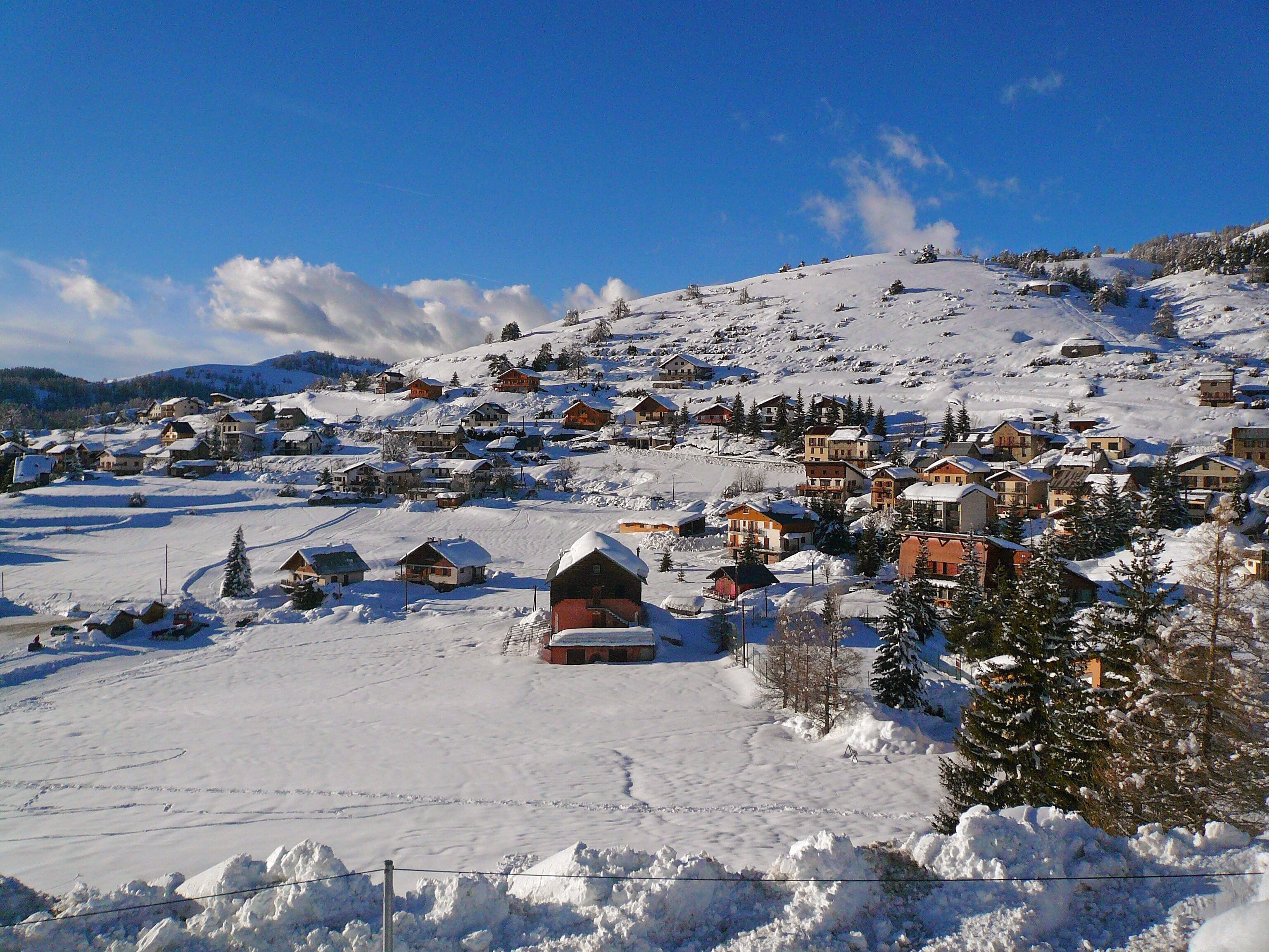 A snow-covered village with houses and a ski slope.