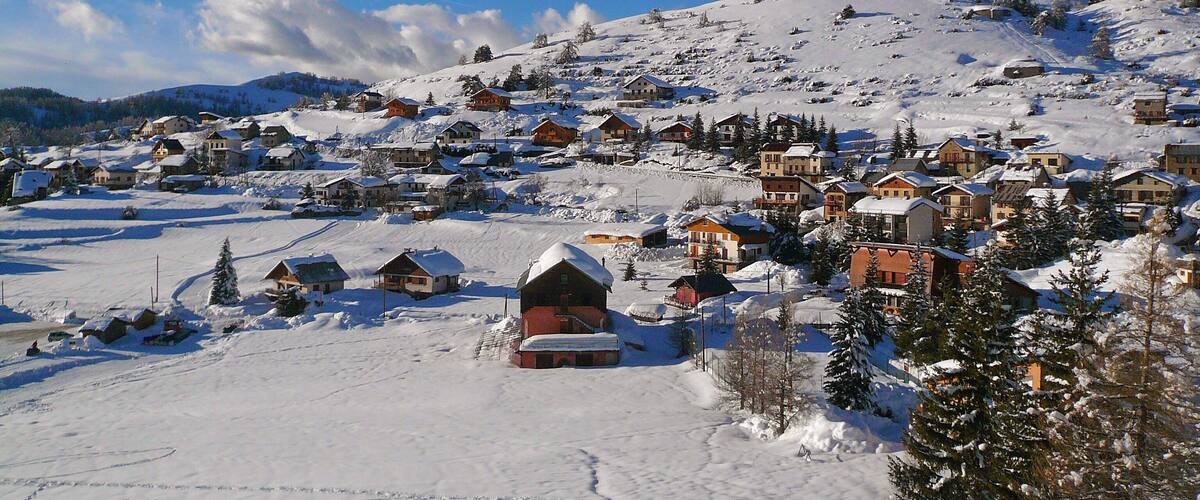 A snow-covered village with houses and a ski slope.