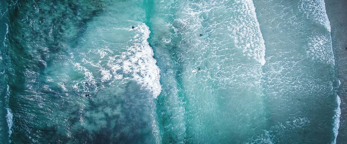 An aerial view of a beach with waves and a surfer.