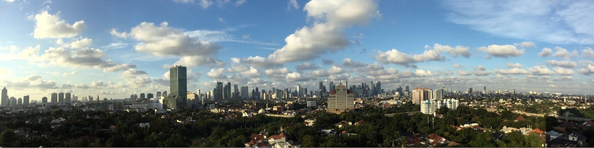 A city skyline with a mix of modern and older buildings under a partly cloudy sky.