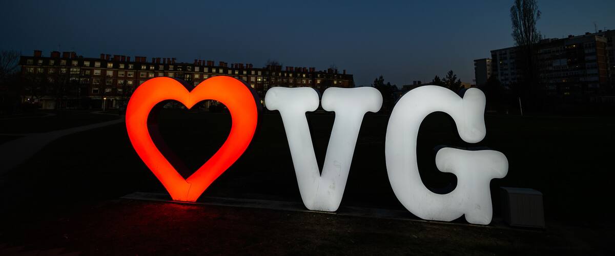 Illuminated letters spelling "LOVE" with a heart shape in the middle, set against a dark sky.