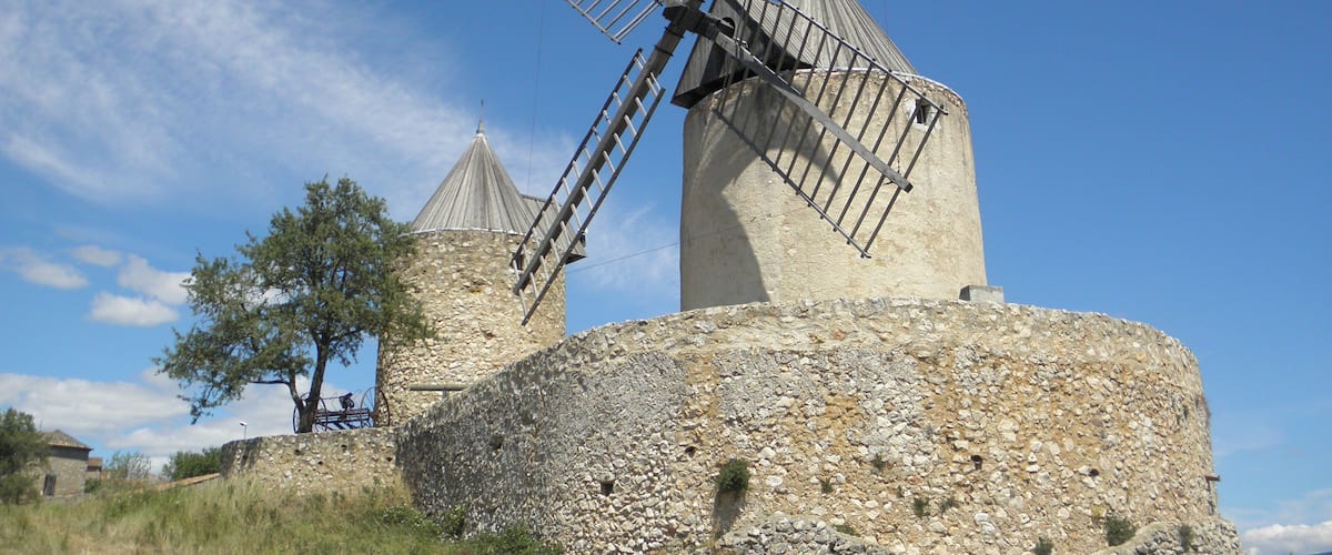 A windmill with a stone base and a metal windlass.
