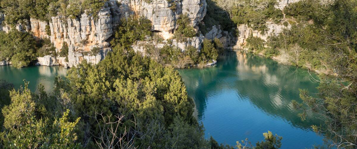 A lake surrounded by rocky cliffs and dense forest.