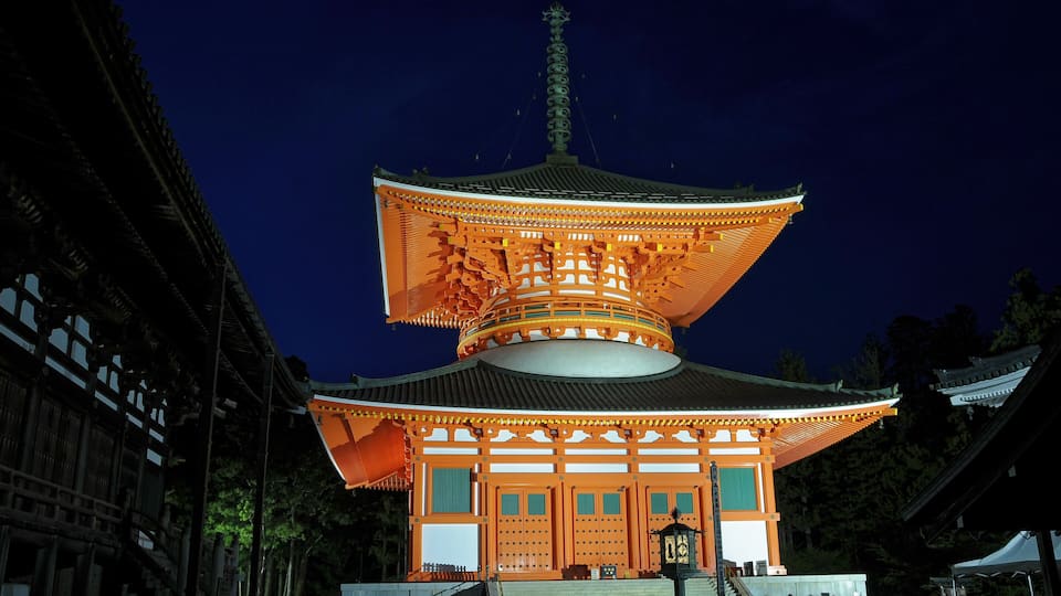 A traditional Japanese pagoda with a multi-tiered roof, illuminated by warm lighting.