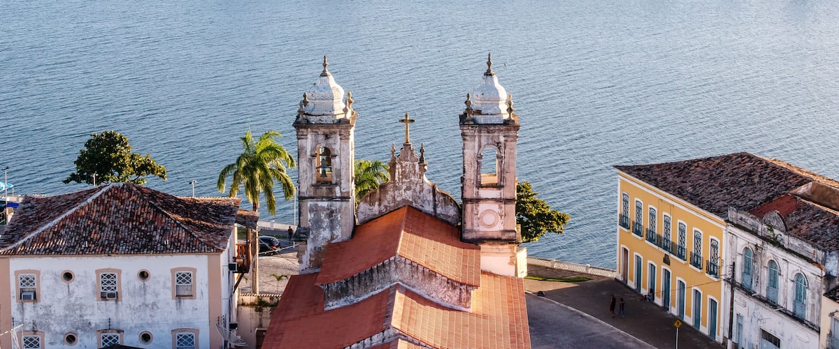 A historic church with two bell towers and a river in the background.