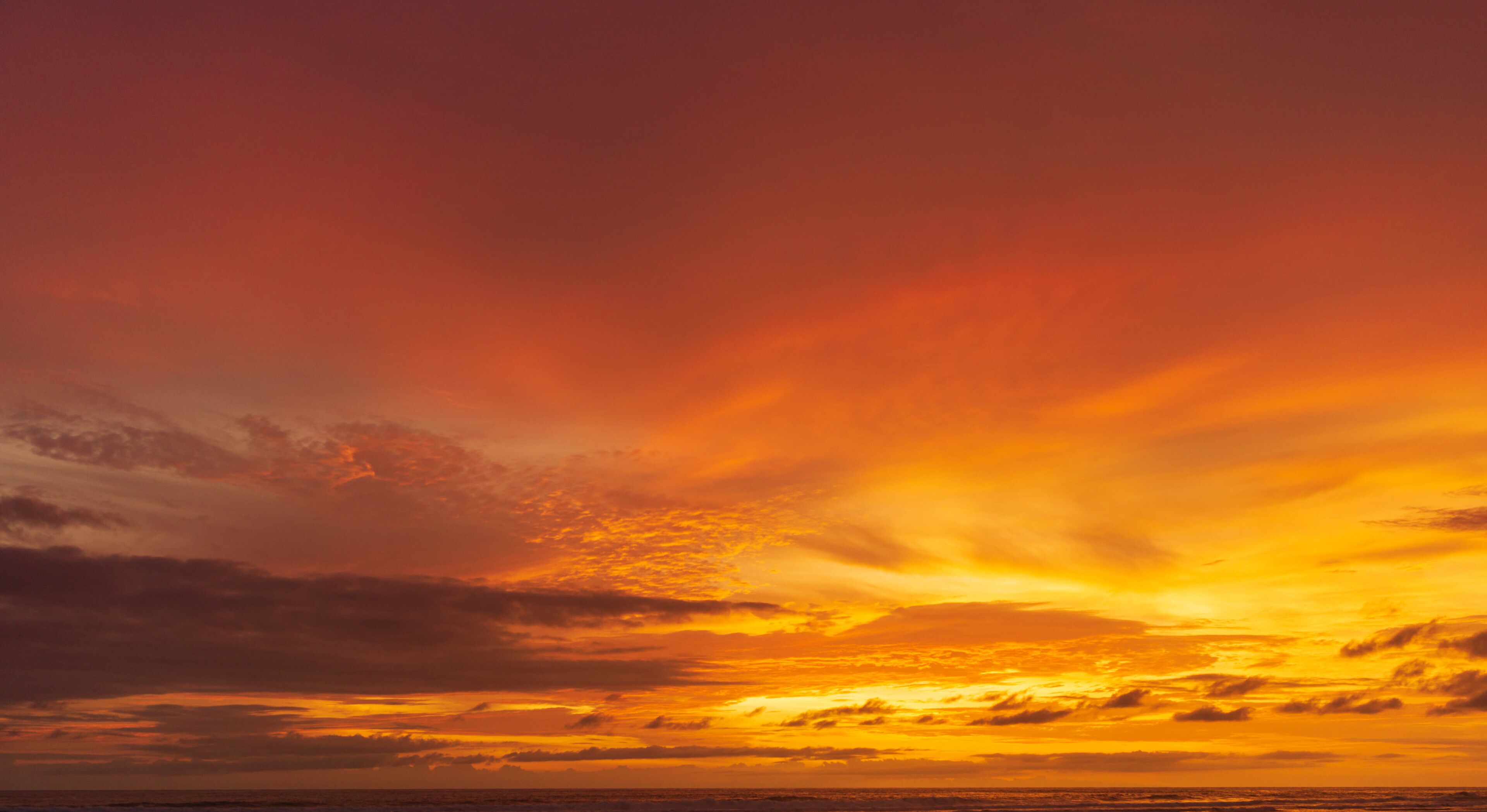 A sunset over the ocean with vibrant orange and yellow hues in the sky.