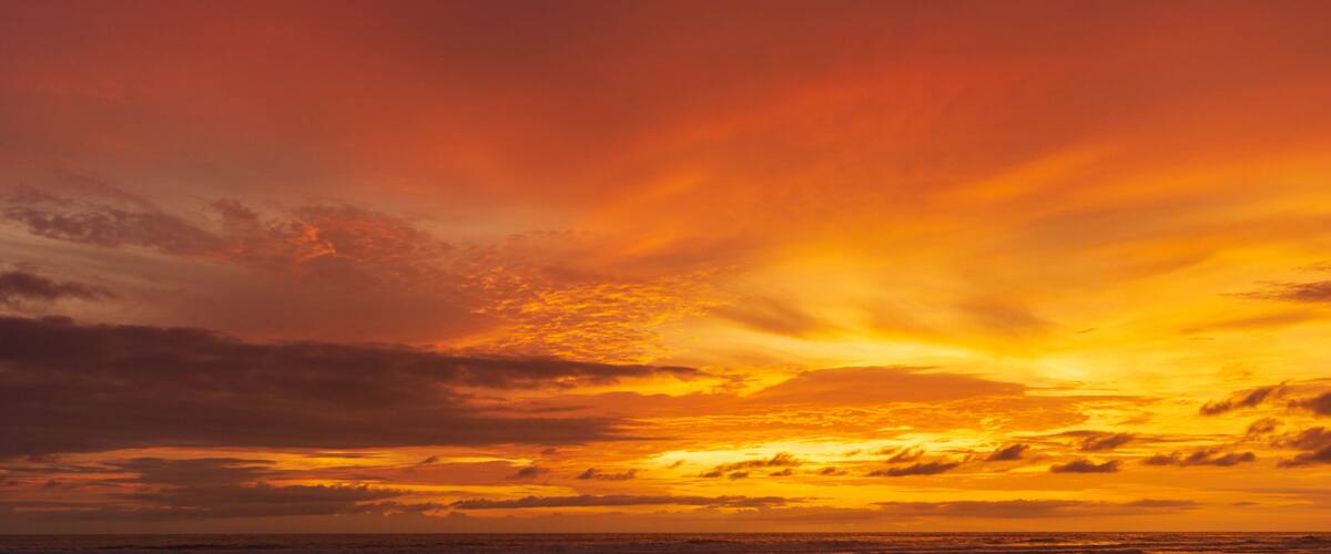 A sunset over the ocean with vibrant orange and yellow hues in the sky.