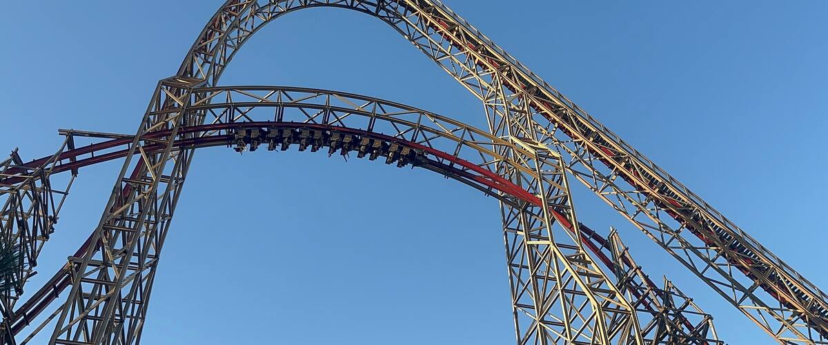 A roller coaster with a steep drop and a large arch.