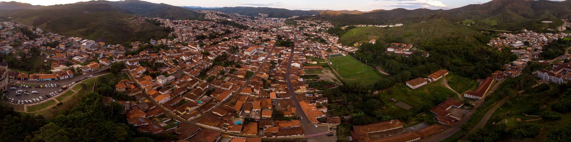 Aerial 360 degrees panorama of a Minas Gerais valley with the colonial mining city and former gold capital Mariana in Brazil at sunset against a blue sky with clouds