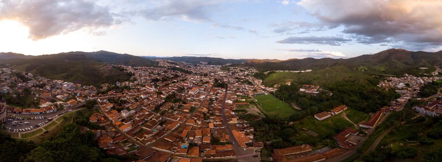 Aerial 360 degrees panorama of a Minas Gerais valley with the colonial mining city and former gold capital Mariana in Brazil at sunset against a blue sky with clouds