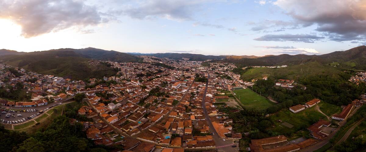 A panoramic view of a town nestled in a valley with surrounding hills, featuring a dense cluster of buildings and a prominent church.