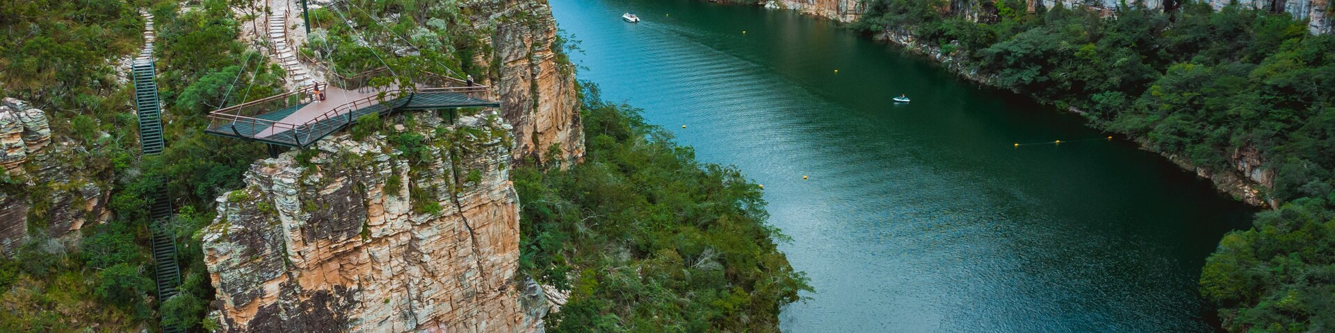 A river winding through a canyon with a bridge and a boat.