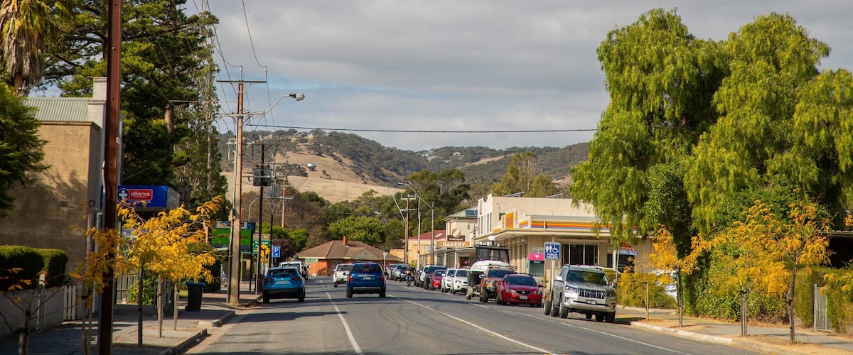 A street lined with cars, a bakery, and a pharmacy.