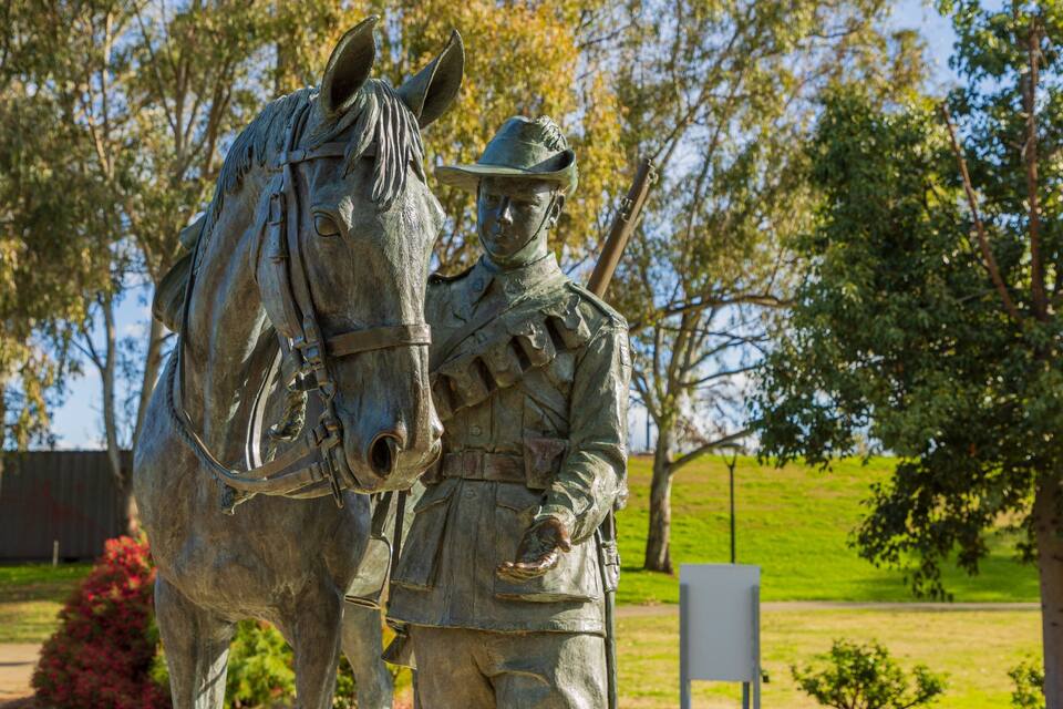 A statue of a mounted figure with a horse in a park.