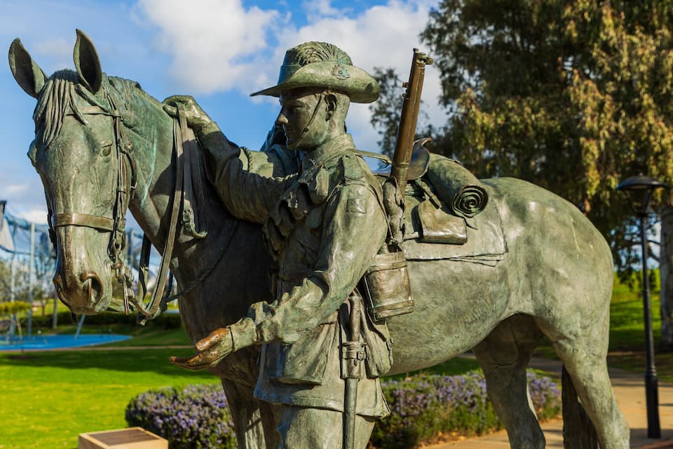 Una estatua de bronce muestra una figura a caballo en un parque.