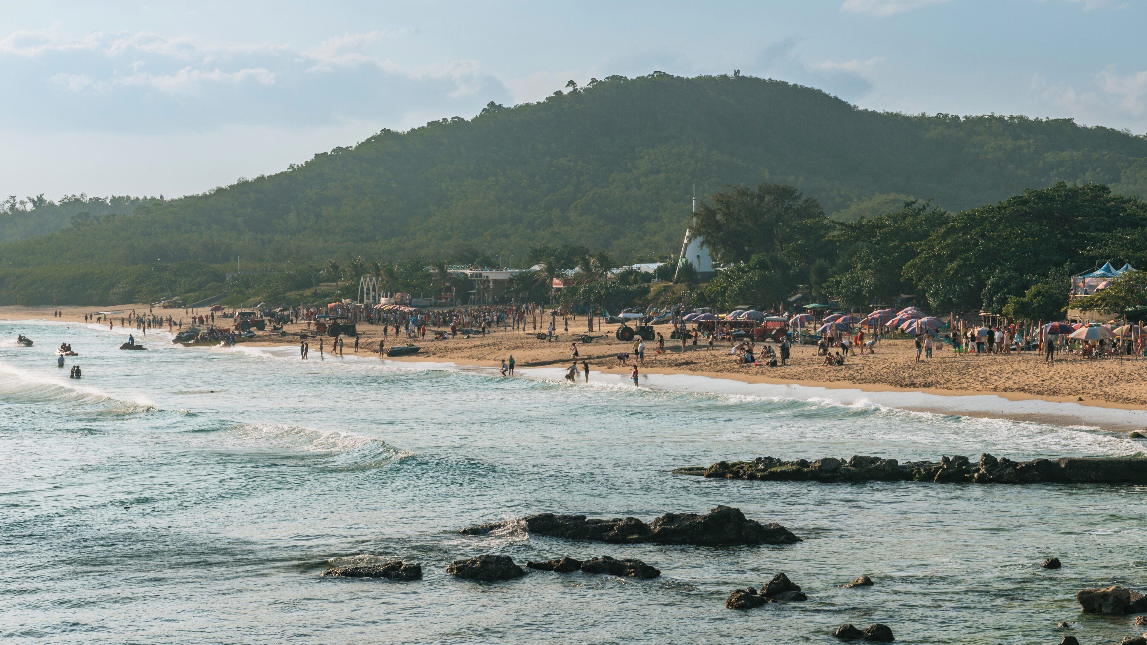Explore the stunning Nan Wan Beach in Hengchun, Taiwan, with vibrant crowds enjoying sunny skies and beautiful waves during a lively beach day