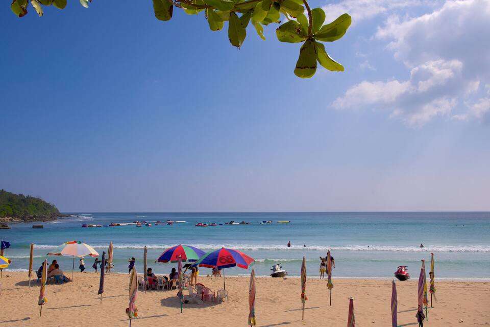 A beach with umbrellas, people, and boats.