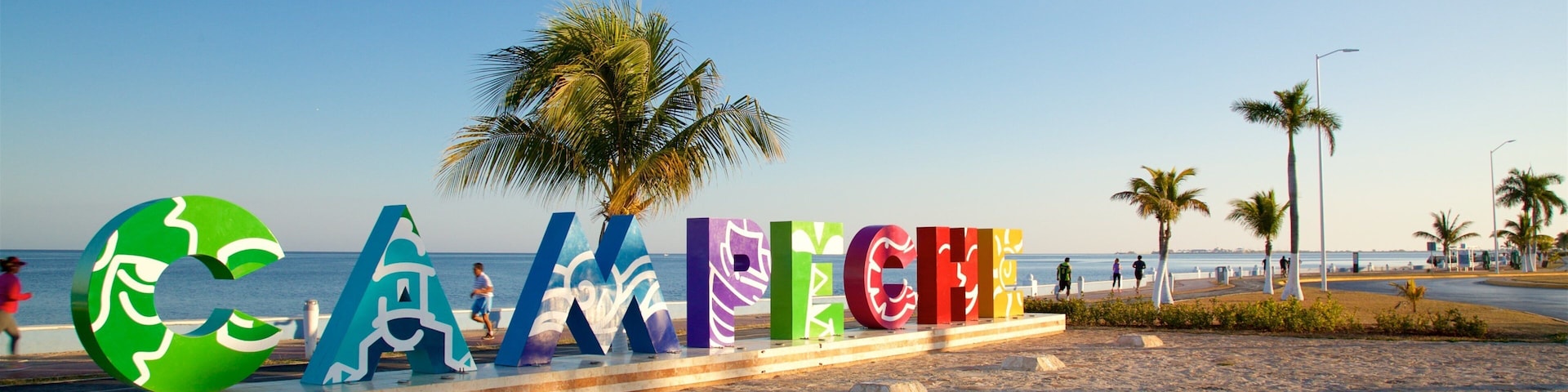 Large colorful letters spelling "CAMDEN" on a beach with palm trees and a clear sky.