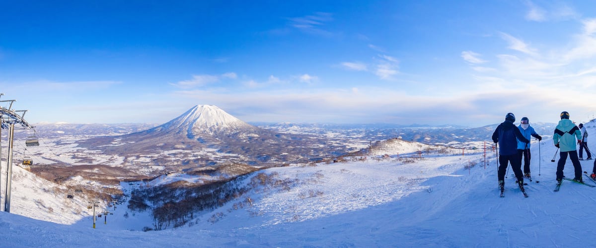 A snowy mountain landscape with a ski lift and skiers.
