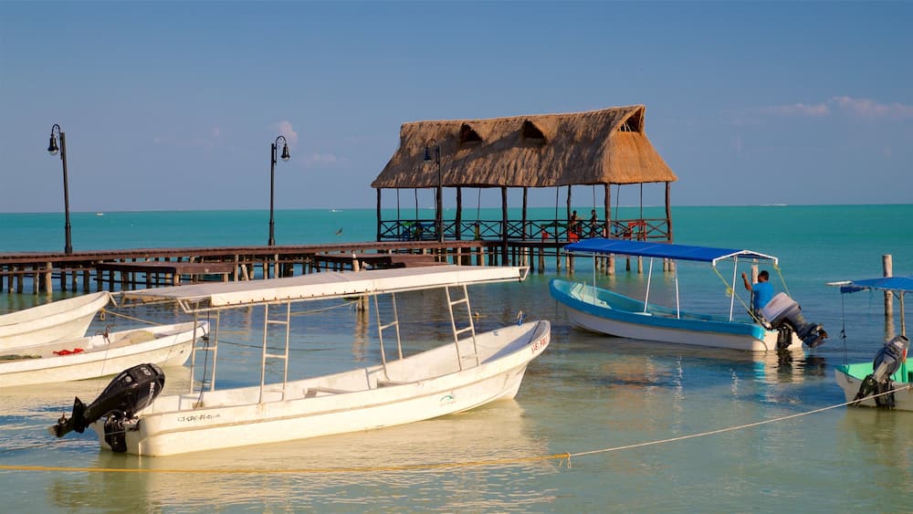 A pier with several boats docked, a thatched-roof structure, and a clear blue sea.