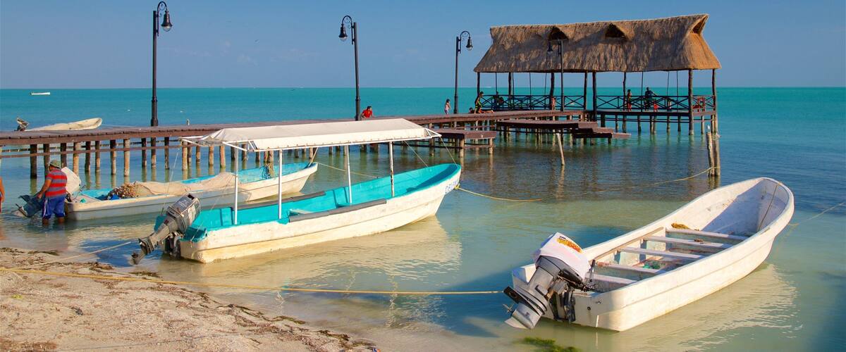 A pier with boats, a thatched-roof structure, and clear turquoise water.