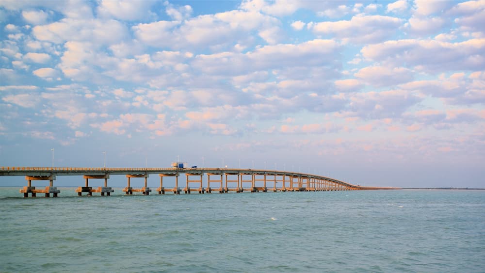 A long bridge over calm water under a partly cloudy sky.