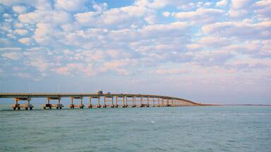 Un puente extenso sobre aguas tranquilas bajo un cielo parcialmente nublado.