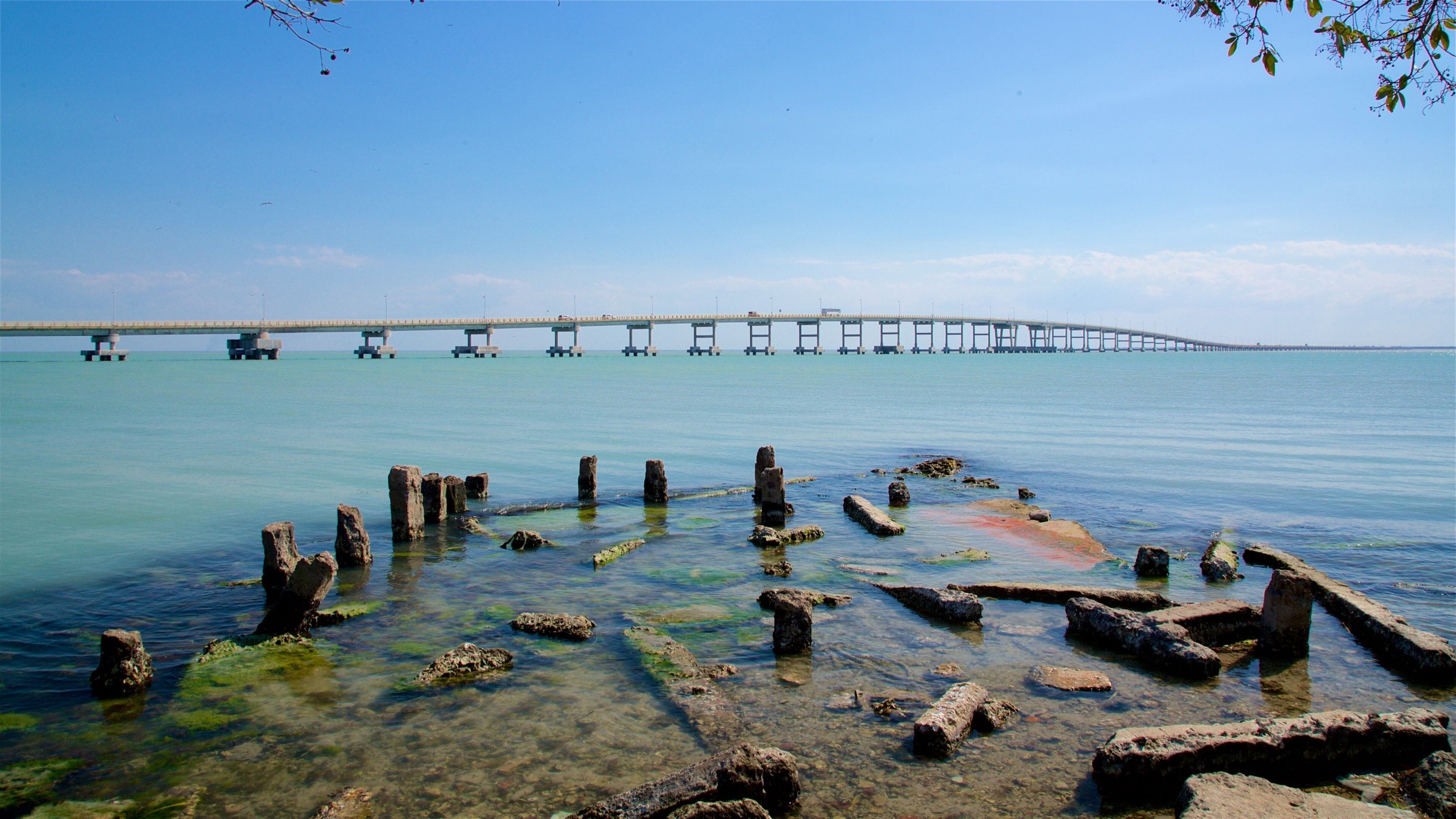 A coastal scene with a pier extending into the water, surrounded by rocky formations.