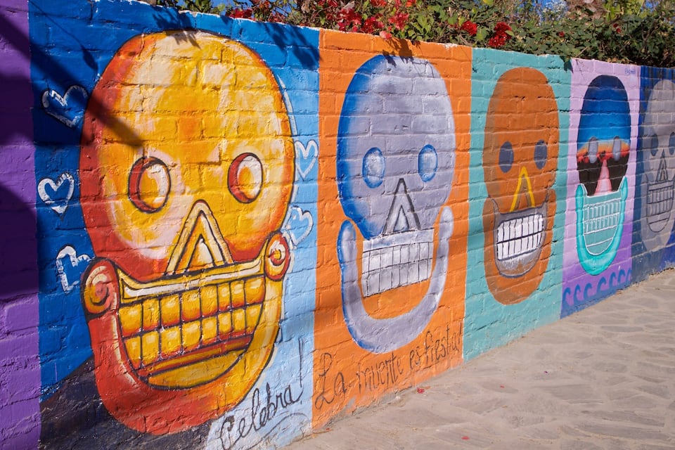 Un murale colorato raffigura teschi e testo su una parete.