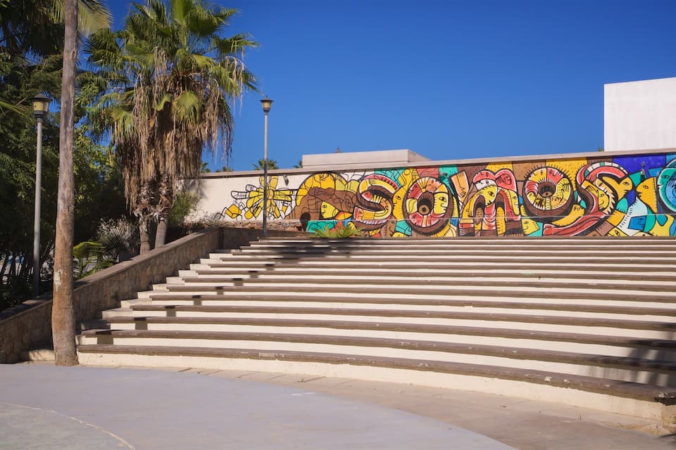 Una scala conduce a un murale colorato con la scritta 'DESOMOS'.