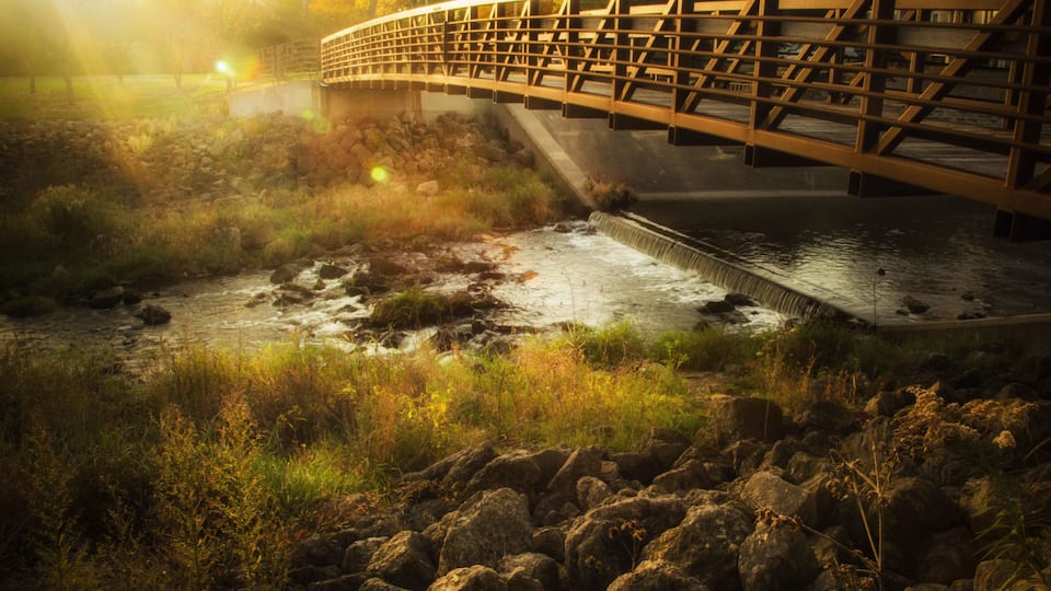A wooden bridge over a river with surrounding rocks and vegetation.